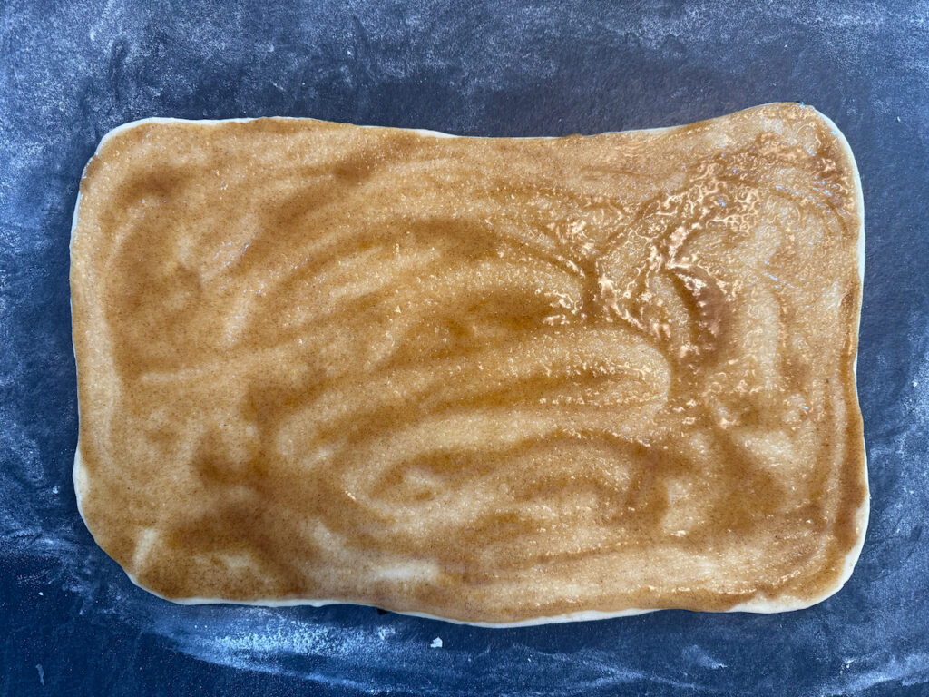 Butter mit Zimt und Zucker mischen und auf dem Teig verteilen