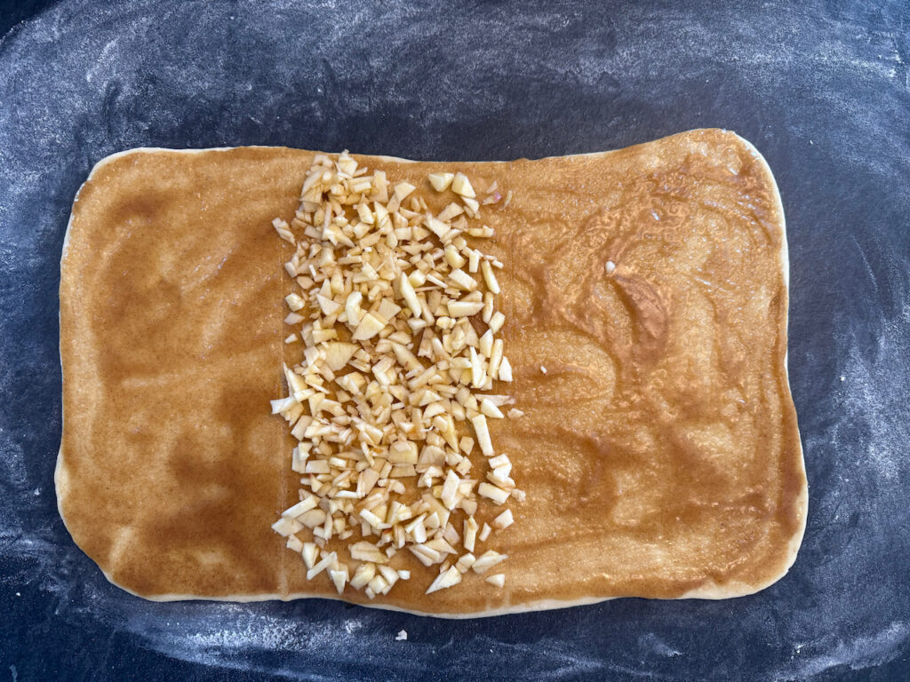 Apfel schälen und sehr fein schneiden und in der Mitte des Teiges verteilen