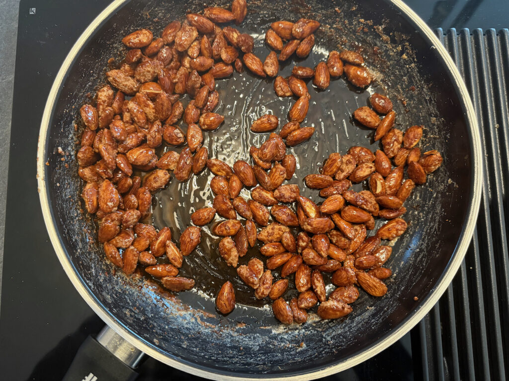 Mandeln ständig rühren, bis der Zucker sich glänzend um sie gelegt hat