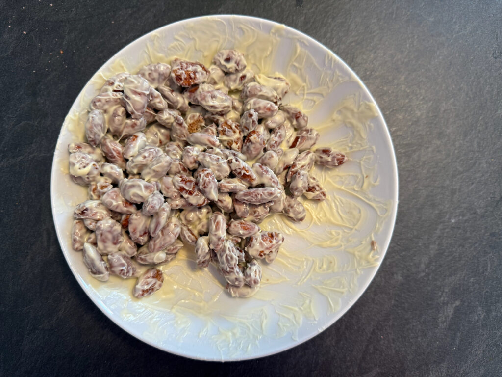 Schokolade schmelzen und die Mandeln damit umhüllen