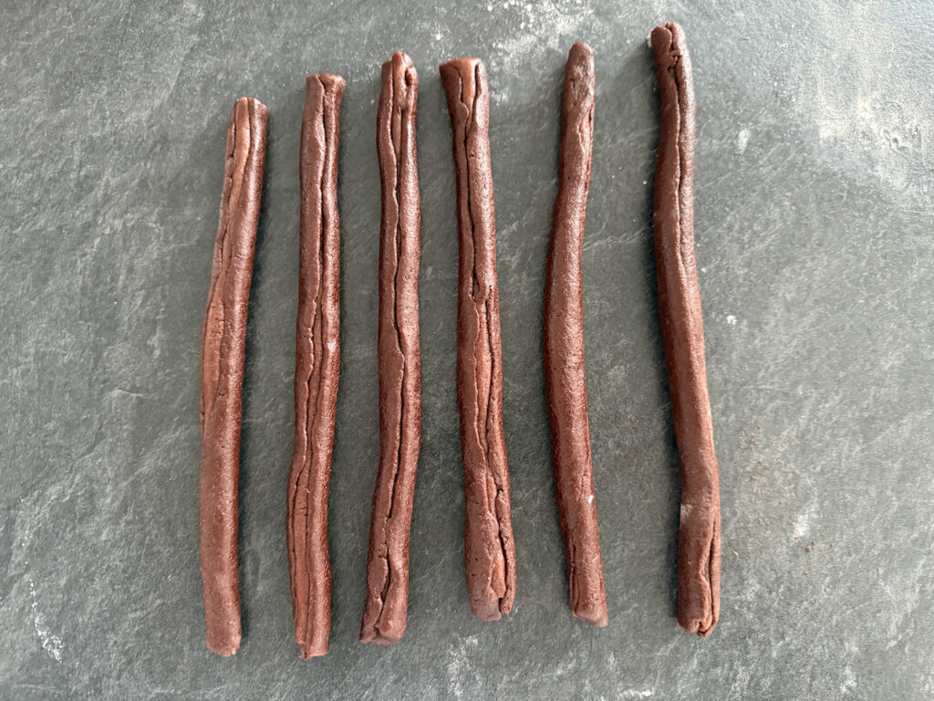 den dunken Teig ausrollen und um die Würstchen wickeln