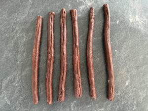 den dunken Teig ausrollen und um die Würstchen wickeln